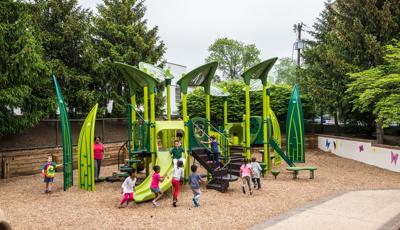 Children clamor and play on this custom playscape which is designed to look like you are playing in the garden with lots of green and leaf climbers. 