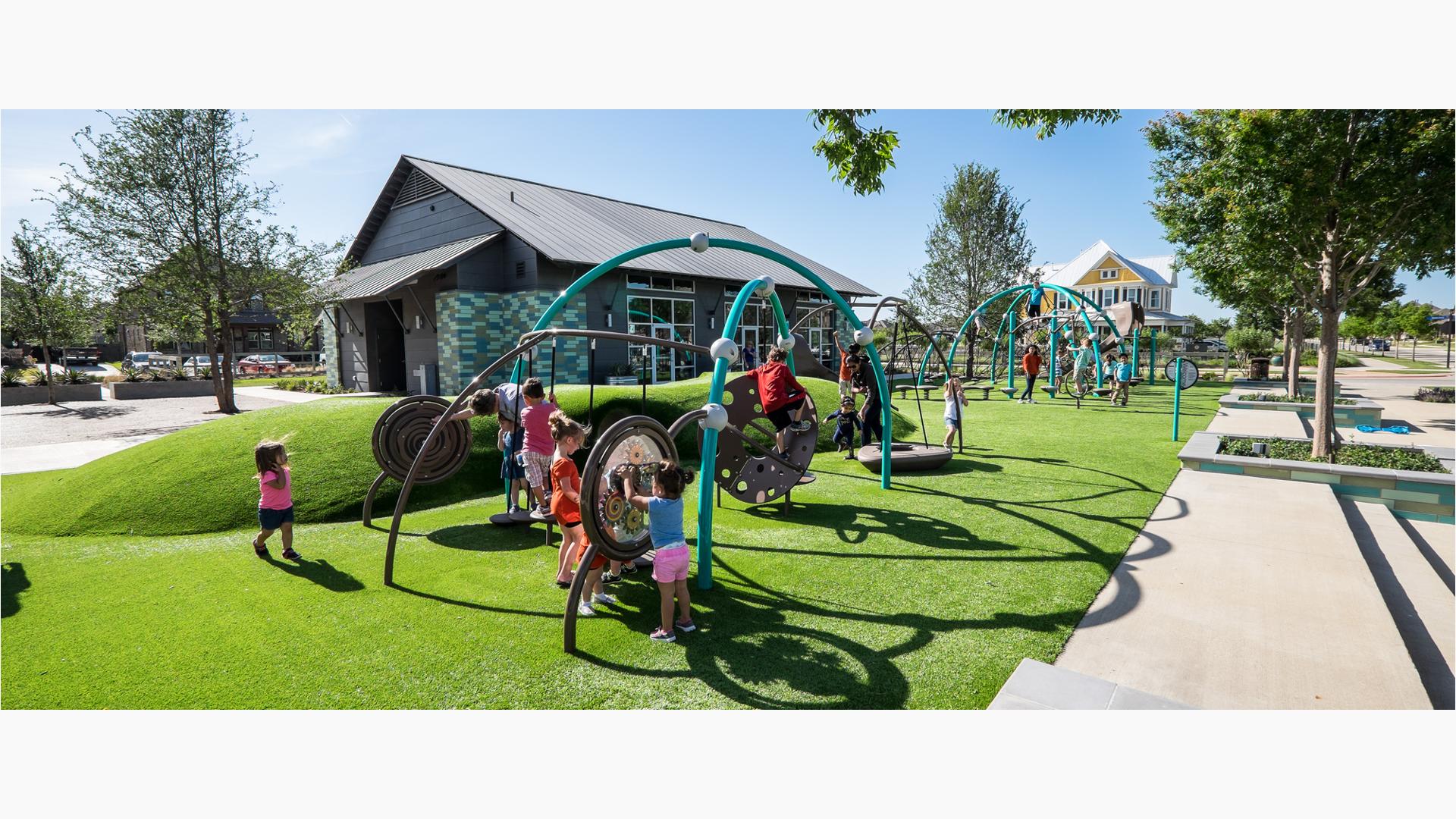 Children play on green grass  with Evos and Weevos play structures.