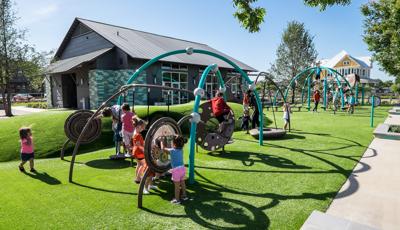 Children play on green grass  with Evos and Weevos play structures.