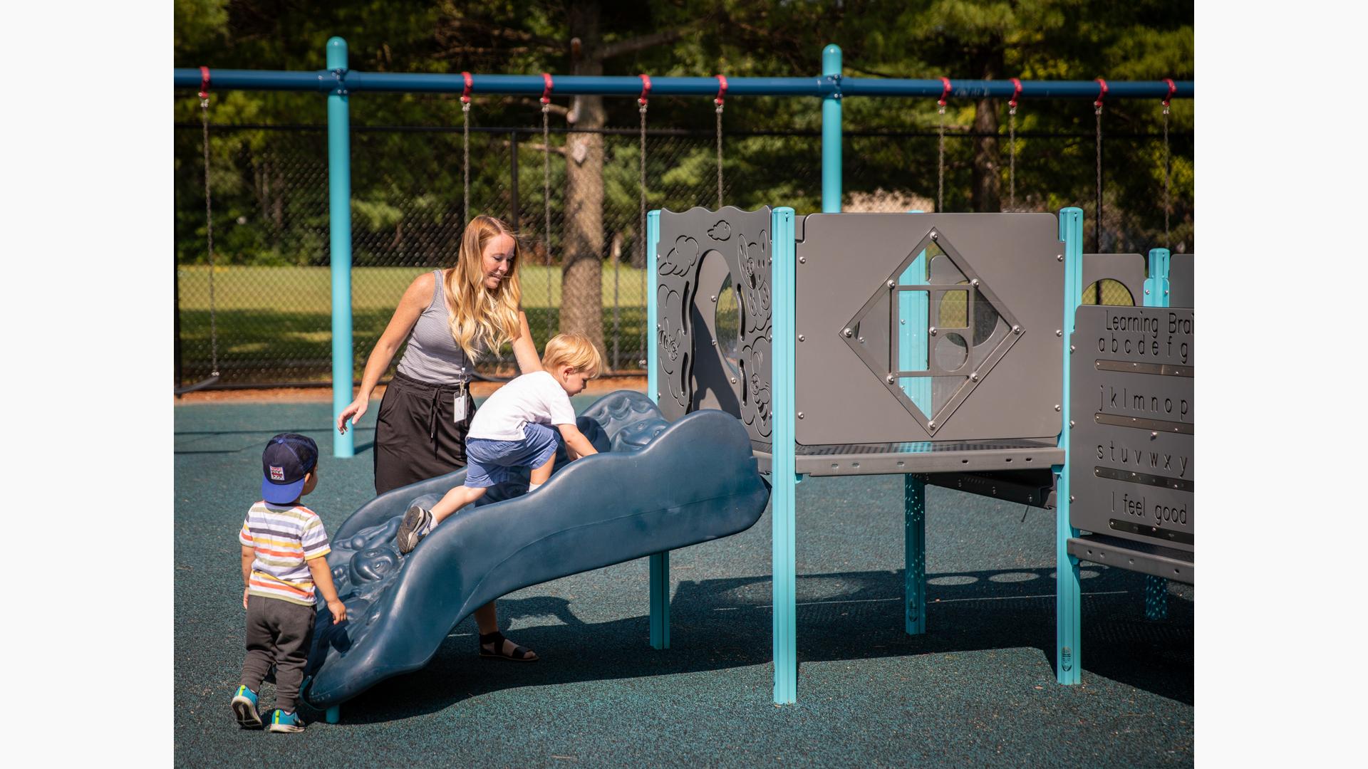 Teacher with helping boys play on PlayShaper® playstructure