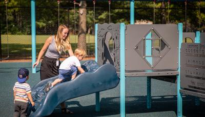 Teacher with helping boys play on PlayShaper® playstructure