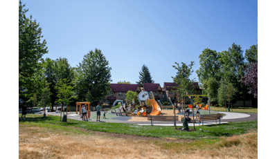 Groups of children playing on a geometric shaped playground surrounded by trees