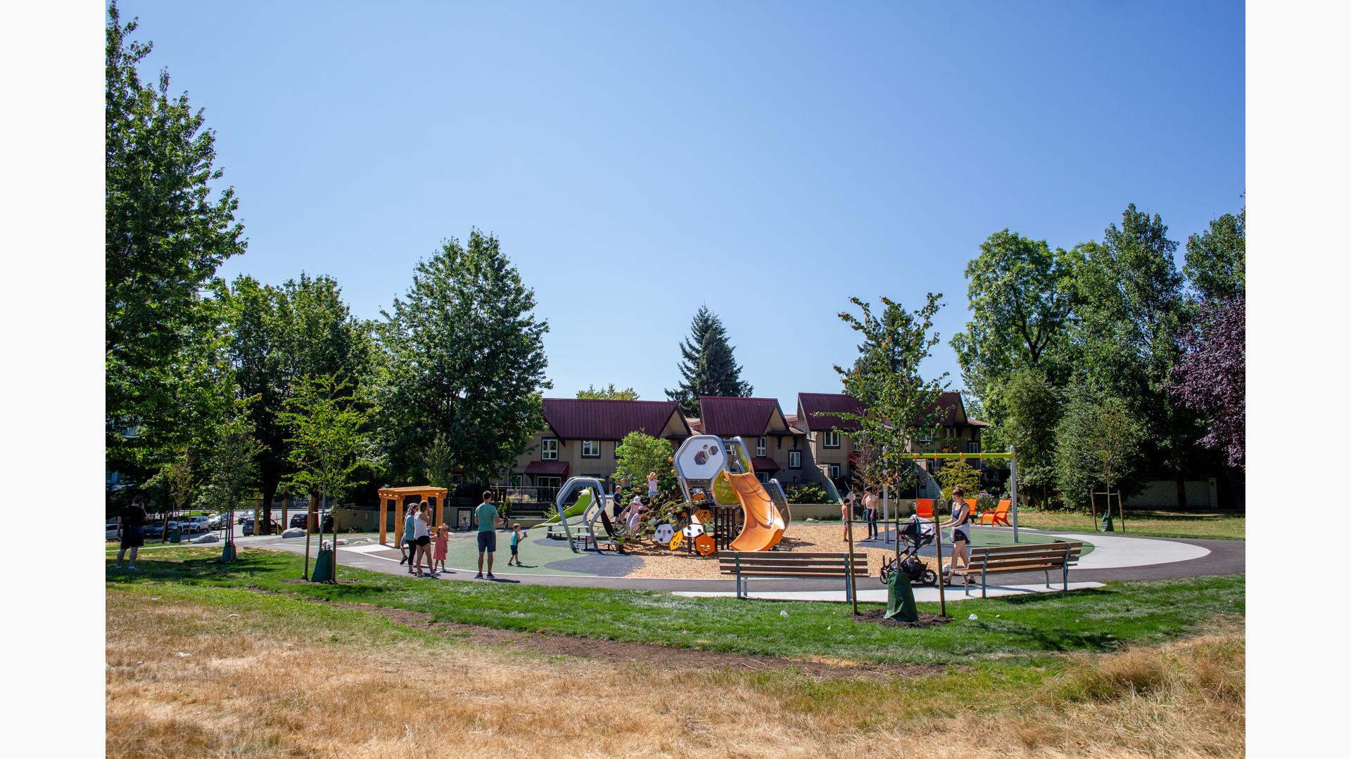 Groups of children playing on a geometric shaped playground surrounded by trees