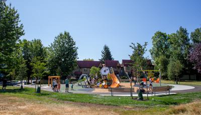 Groups of children playing on a geometric shaped playground surrounded by trees