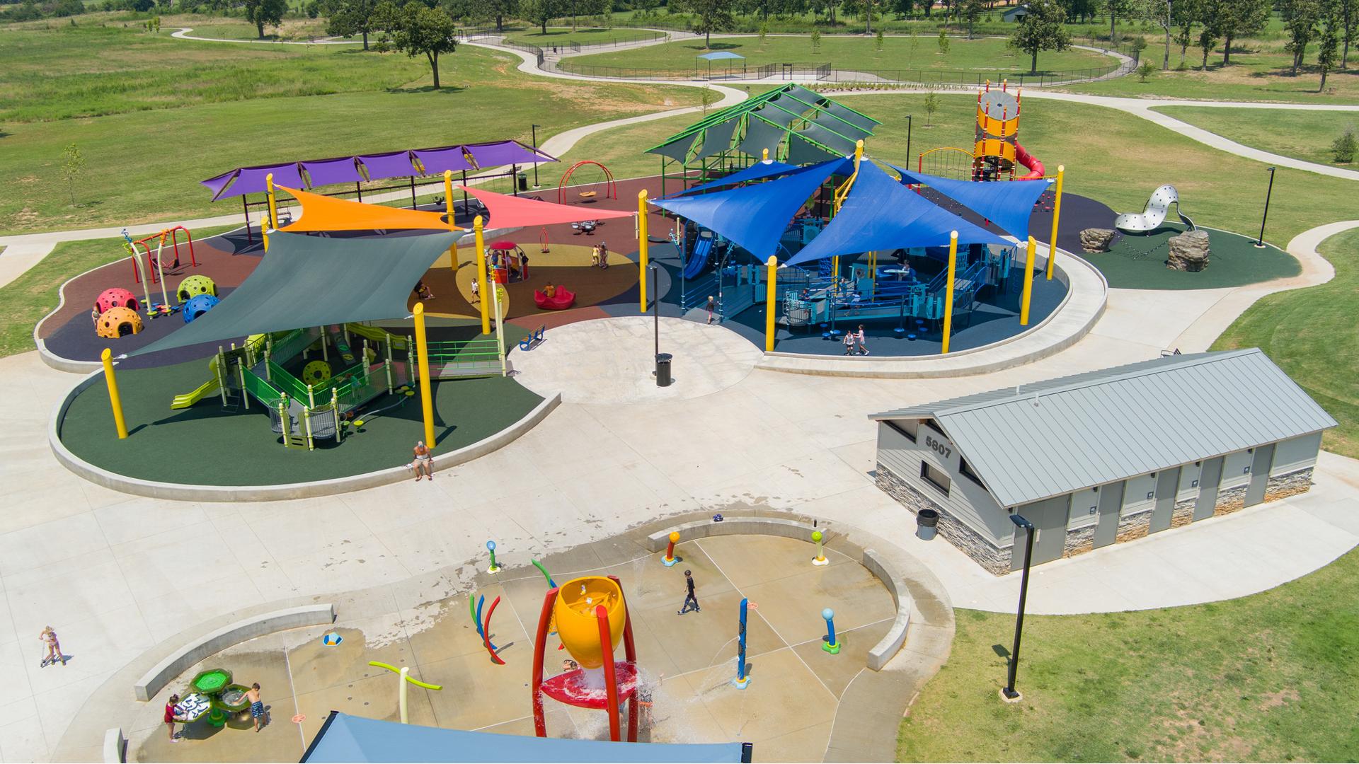 Elevated view of a large play space with corresponding colored shades sails to match the playground coloring below.