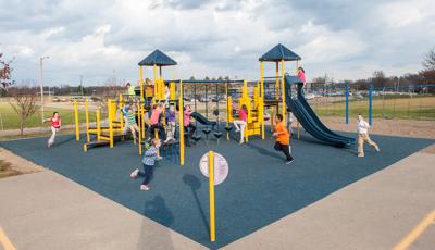 despite the wind and clouds, children at Notre Dame Elementary run and and play on  PlaySense  play structure. 