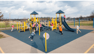 despite the wind and clouds, children at Notre Dame Elementary run and and play on  PlaySense  play structure. 