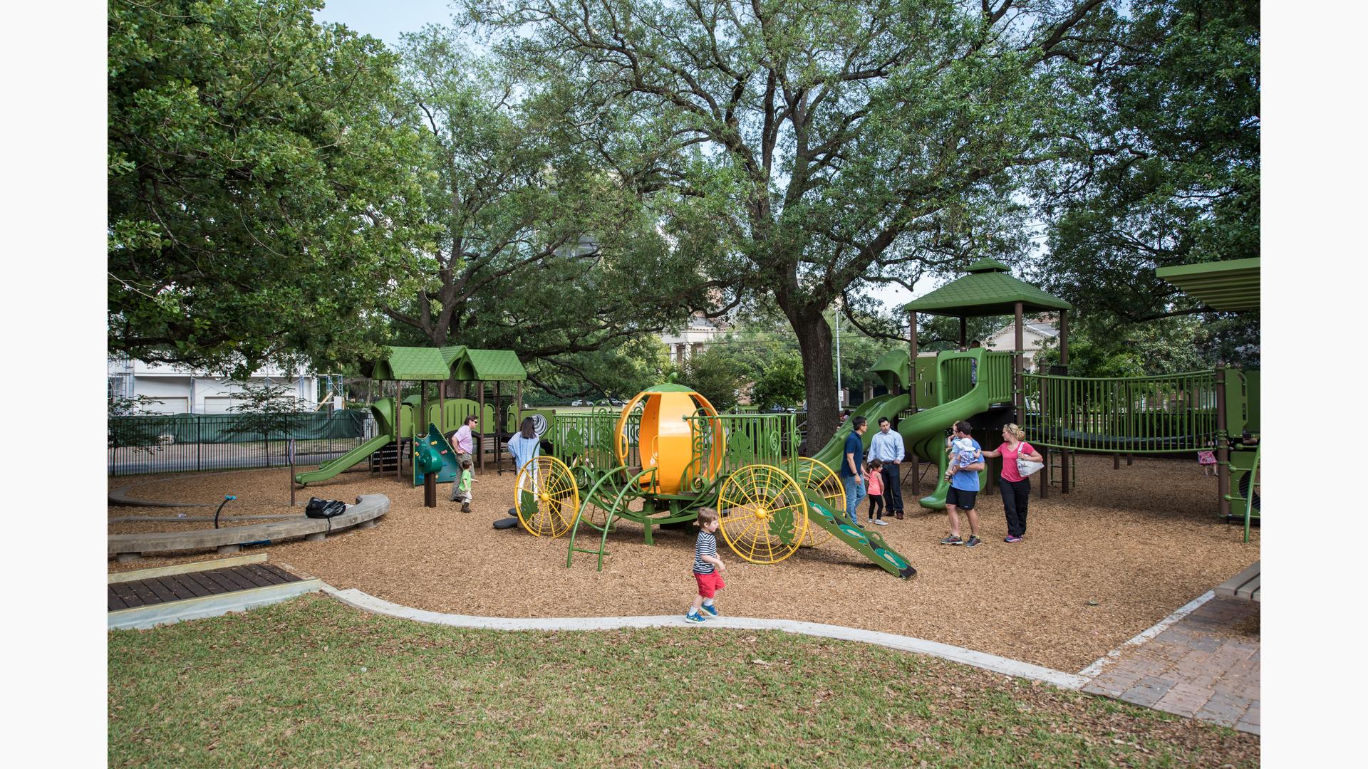 A little boy walks across a strip of concrete as families gather round the newly renovated "Pumpkin park" and enjoy the new play structures.