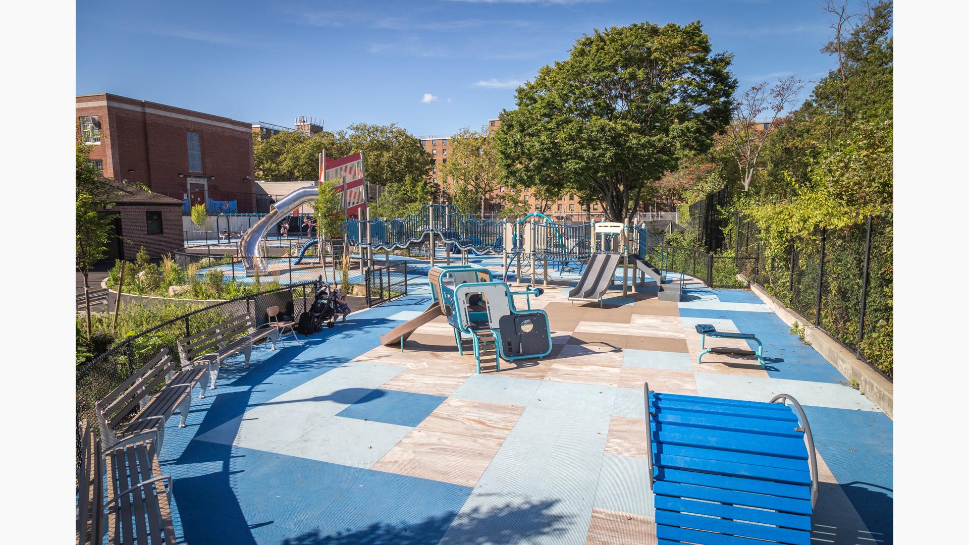 Red-striped playground tower with stainless steel slide and connects to a wavy looking bridge.  Play space also includes a geometric square smaller structure for younger kids.