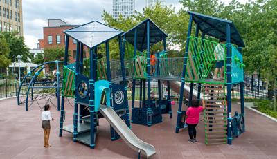 Elevated view of a custom city playground with unique geometrical roofs, wall panels, and climbers.