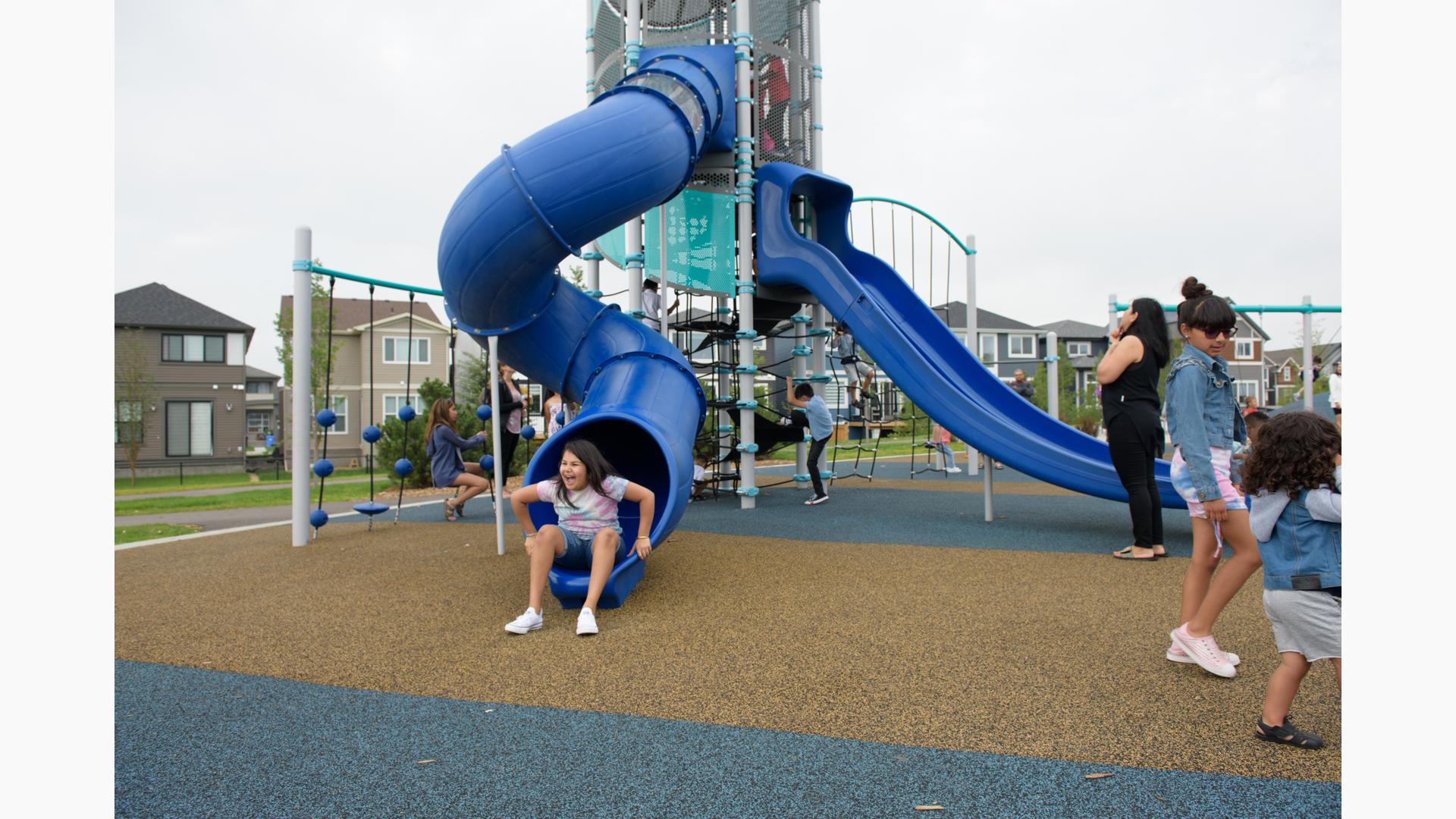 Girl smiling as she climbs out of windy tunnel slide