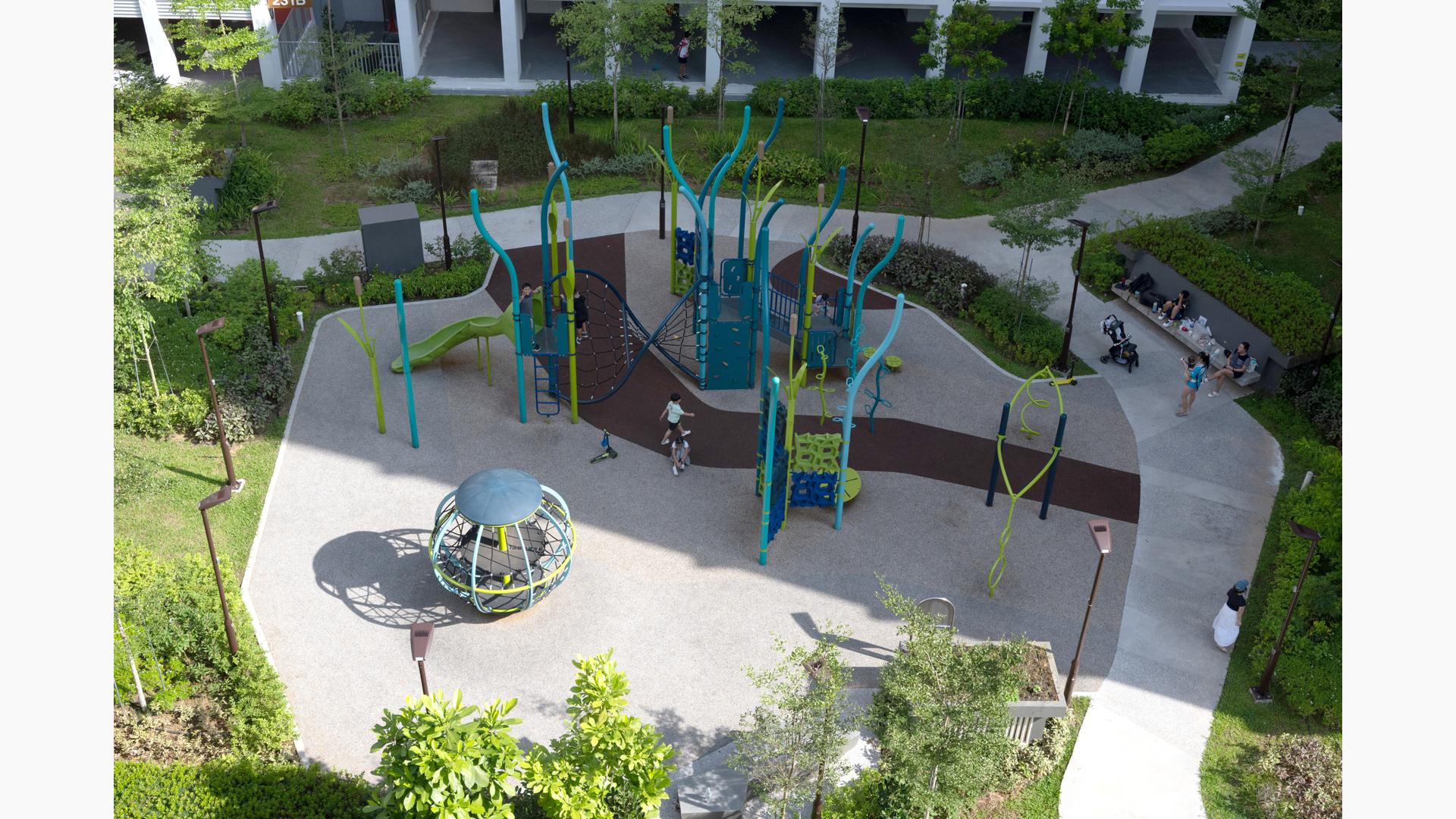 Elevated view of children playing on a park playground amongst apartment buildings.