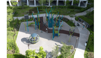 Elevated view of children playing on a park playground amongst apartment buildings.