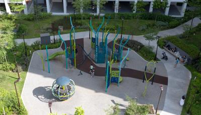 Elevated view of children playing on a park playground amongst apartment buildings.