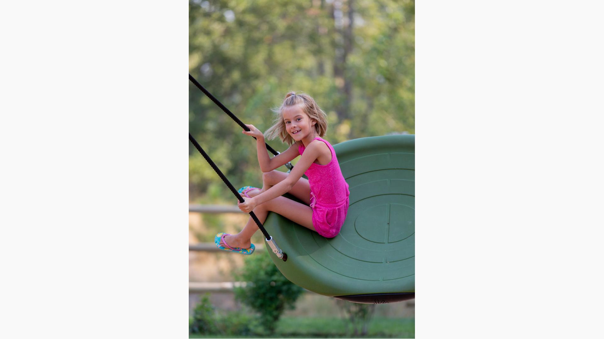 Girl smiling swinging on Oodle® Swing