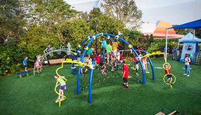 Children climber and play on crisscrossed ropes connected to blue arched posts with custom connectors designed as eyeballs playing into the playground's movie theme of Mosters Inc.