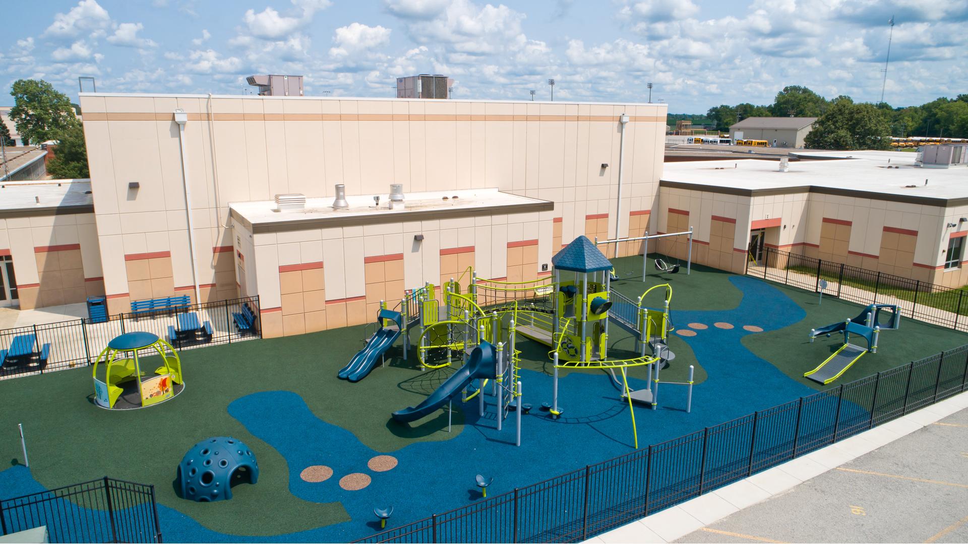 Elevated view of a inclusive playground set next to a school building.