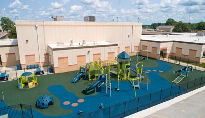 Elevated view of a inclusive playground set next to a school building.