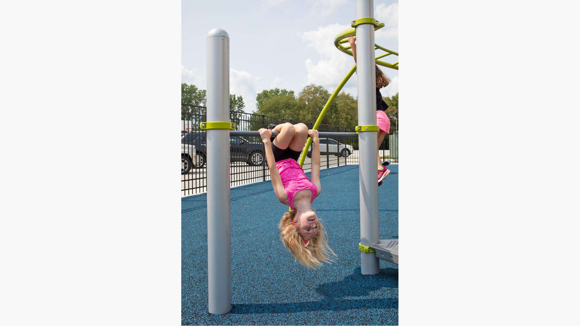 Girl hanging upside down on Chinning/Turning Bar