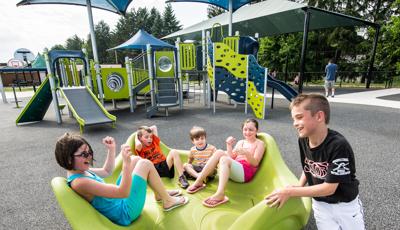 Boy in baseball uniform pushing friends on OmniSpin® Spinner