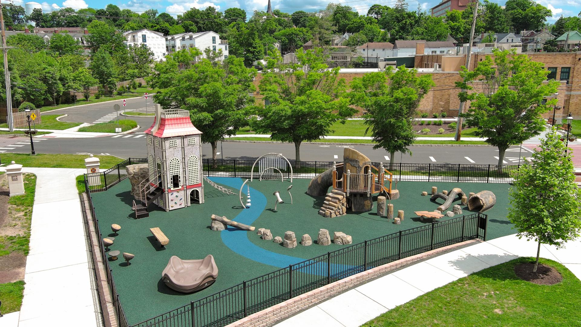 Elevated view of a play area with rock and log climbers with a single building designed play structure.