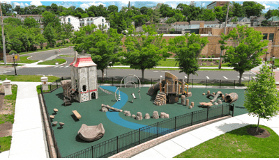Elevated view of a play area with rock and log climbers with a single building designed play structure.