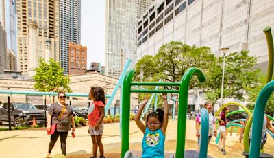 Girl riding slide with both arms up