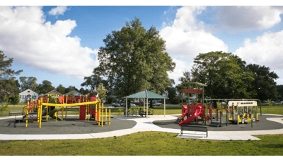 Two playground structures that memorializes Martin Luther King, Jr. are colored in green, red and yellow. A small pavilion sits provides shade to a picnic table between the two play structures.