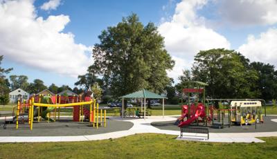 Two playground structures that memorializes Martin Luther King, Jr. are colored in green, red and yellow. A small pavilion sits provides shade to a picnic table between the two play structures.