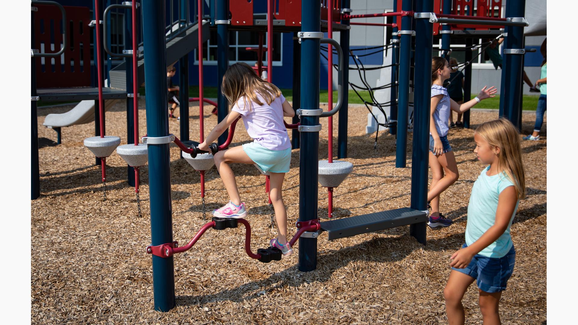 Girl in jean shorts watches friend in purple shirt riding Stationary Cycler