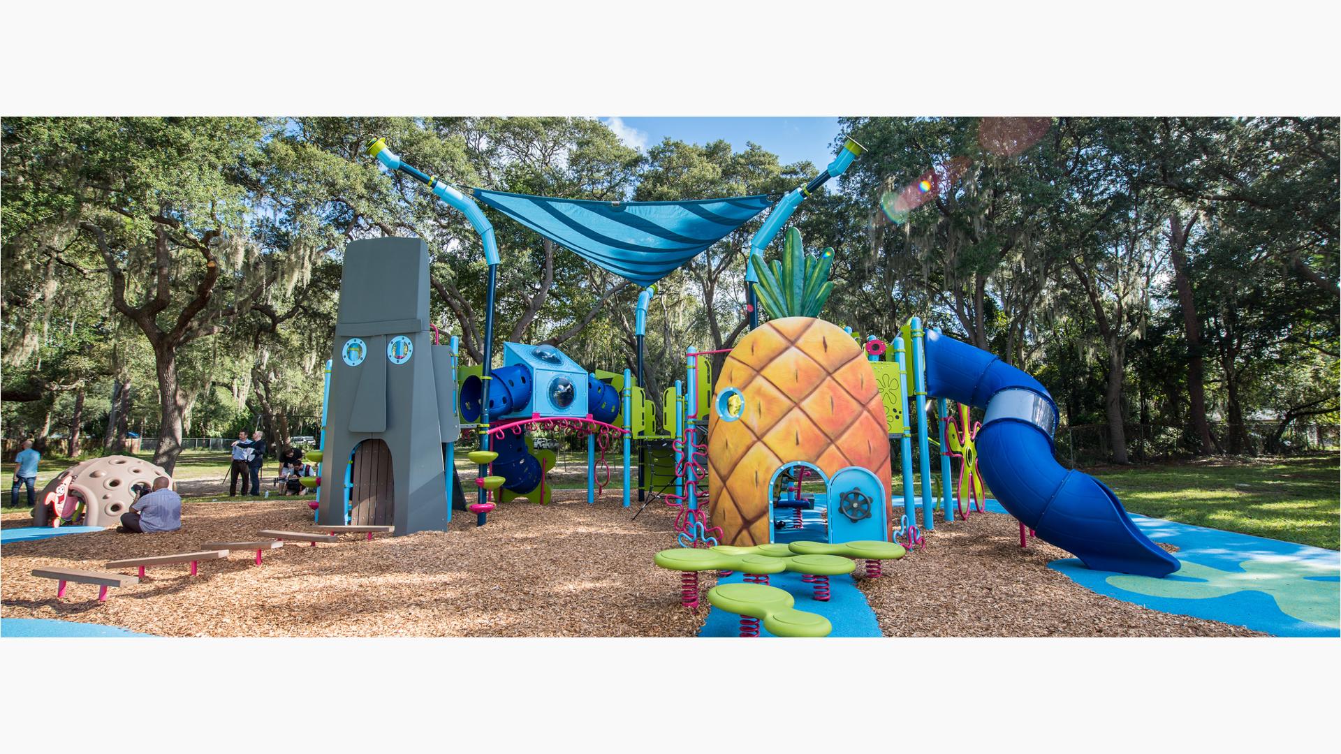 A custom playground designed like the cartoon character Sponge Bob SquarePants pineapple home and his neighbor Squidward’s Easter Island Head home connected by climbers and bridges and other play activities.  