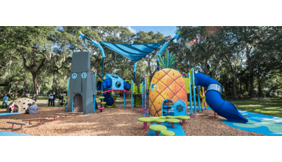 A custom playground designed like the cartoon character Sponge Bob SquarePants pineapple home and his neighbor Squidward’s Easter Island Head home connected by climbers and bridges and other play activities.  