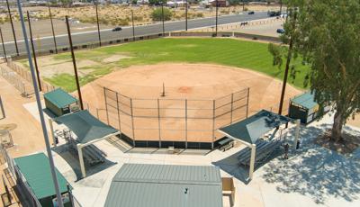 Elevated view of a softball field with green rectangular shade cantilevers over either side of the fan bleachers.